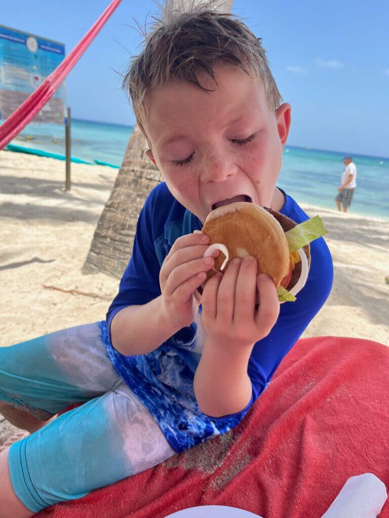 Boy eating burger on the beach in Cozumel Mexico