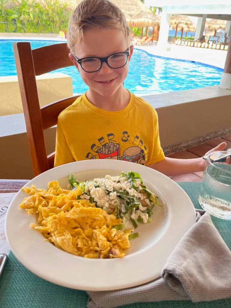 Boy eating lunch by the pool at Sunscape Sabor in Cozumel Mexico